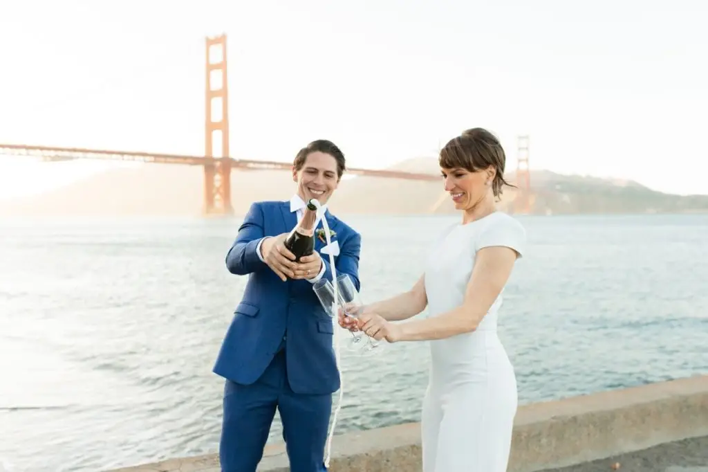 Married couple celebrating with champagne on the beach in San Francisco. 