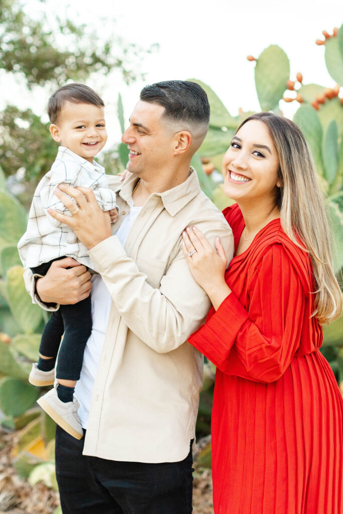 Family posing in front of adobe buildings surrounded by cacti and tall grass at Alviso Adobe.