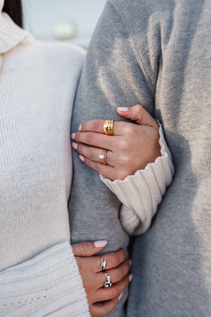 Close-up of couple holding hands, showcasing their accessories.
