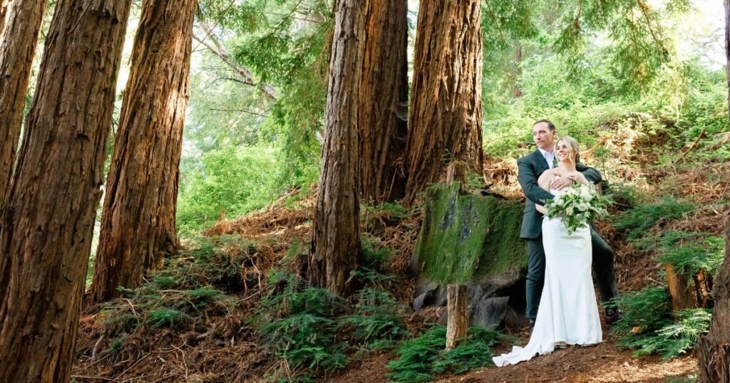 Angela and Mike stand hand in hand through the Redwood grove.